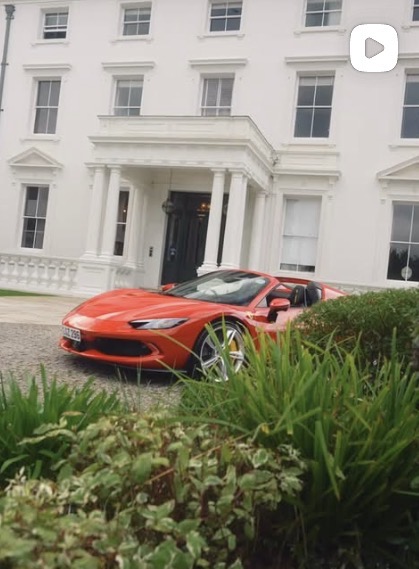 Orange Ferrari convertible parked in front of a grand white mansion