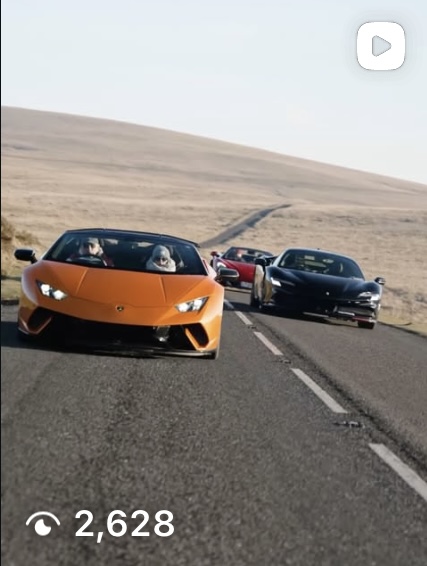 Orange Lamborghini leading a supercar convoy on a winding moorland road