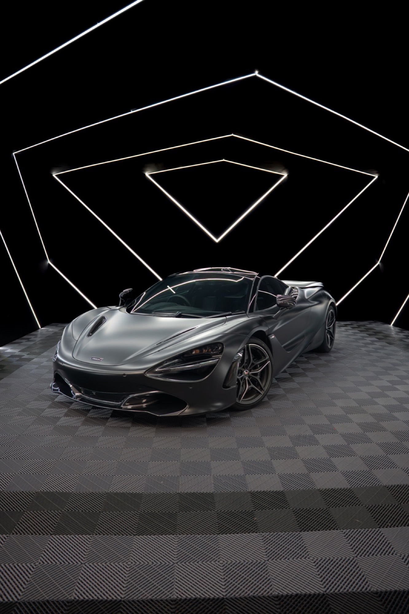 Graphite McLaren 720S Spider in a black studio with LED triangles